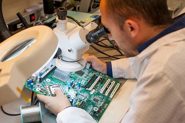 Engineer inspecting a PCB for conformal coating defects under magnification